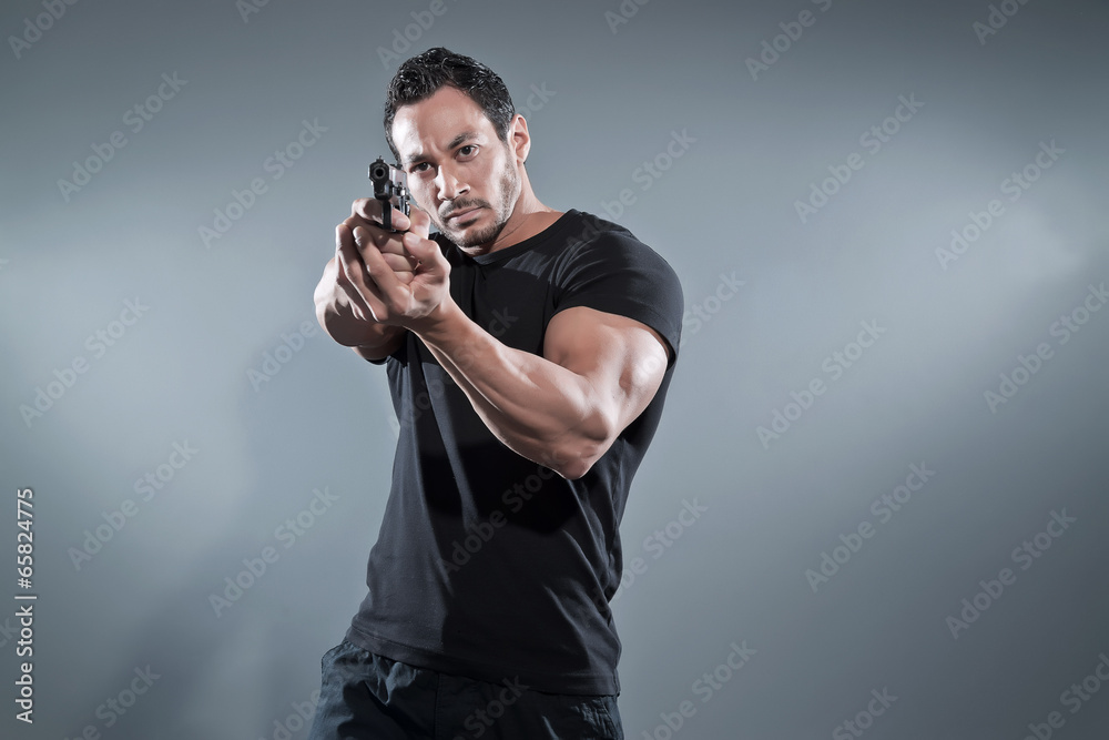Action hero muscled man shooting with gun. Wearing black t-shirt Action hero muscled man shooting with gun. Wearing black t-shirt