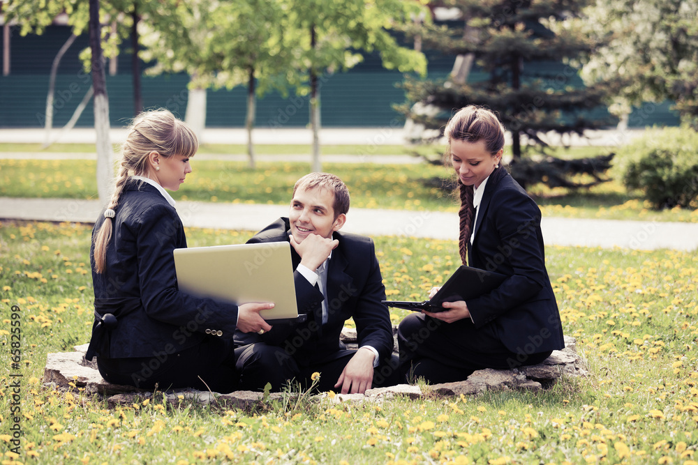 Young business people using laptop in a city park Young business people using laptop in a city park