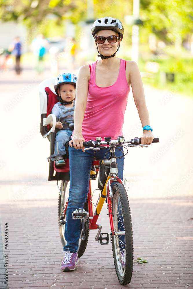 Obraz premium Caucasian young woman on a bicycle with little son behind