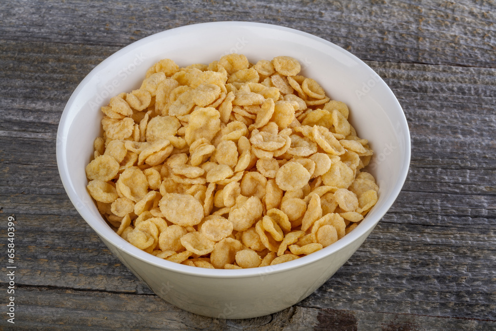 .closeup cornflakes in a bowl on a rustic table .closeup cornflakes in a bowl on a rustic table