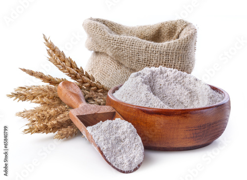 whole grain flour in a bowl and linen bag with a wooden spatula