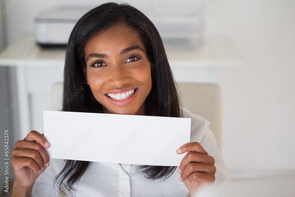 Pretty businesswoman showing white card at her desk Pretty businesswoman showing white card at her desk