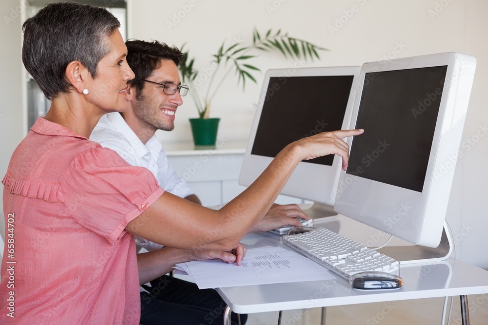 Casual business team working together at desk using computer