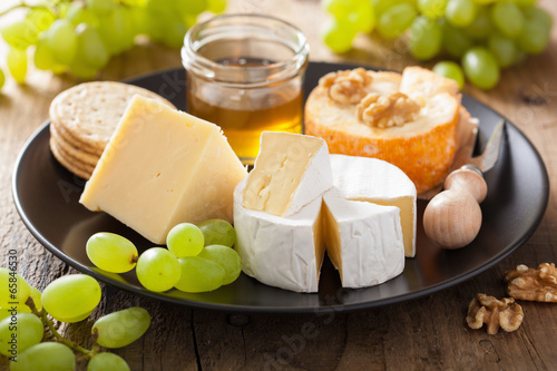 cheese plate with camembert, cheddar, grapes and honey
