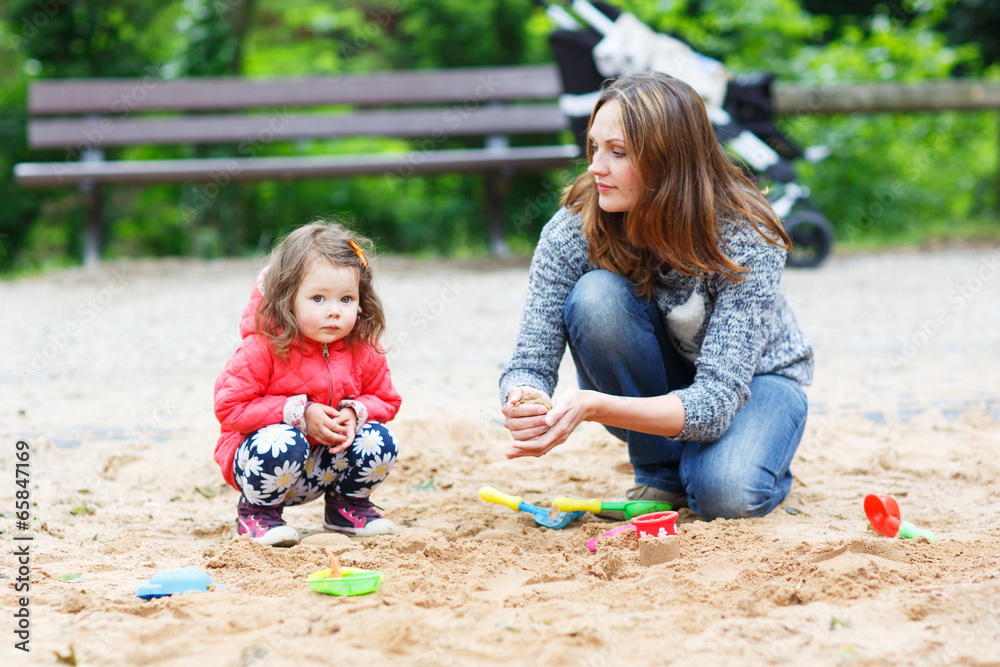 mother and little daughter playing together on playground