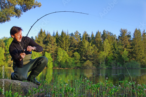 Obraz na płótnie pêcheur aux leurres combattant un poisson dans un lac.