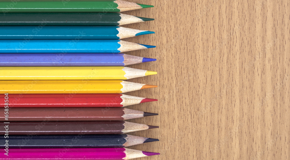 Colored pencils arranged on a wooden table Colored pencils arranged on a wooden table