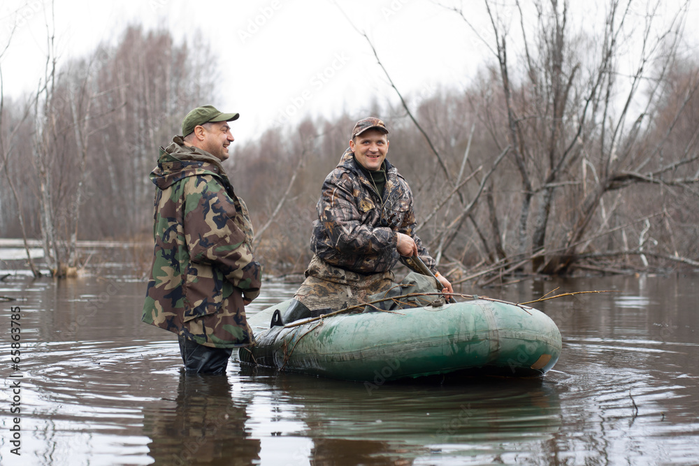 Naklejka premium the hunters put stuffed ducks on water from a rubber boat
