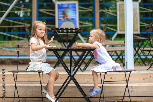 Little adorable girls at outdoor cafe on warm summer day