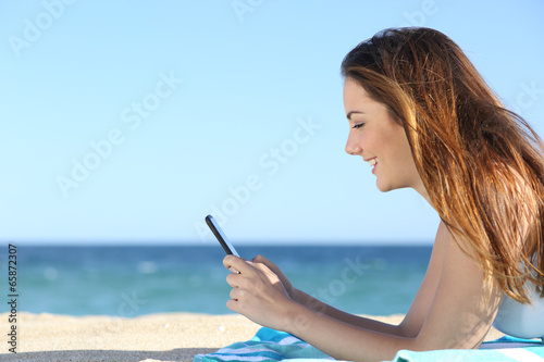 Profile of a woman texting in a smart phone on the beach