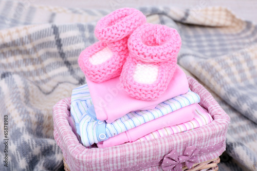 Baby clothes in basket on plaid in room © Africa Studio