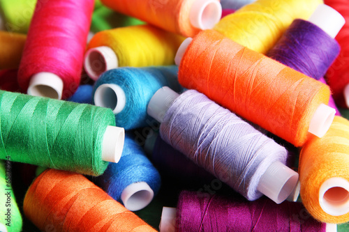 Multicolor sewing threads on wooden background photo