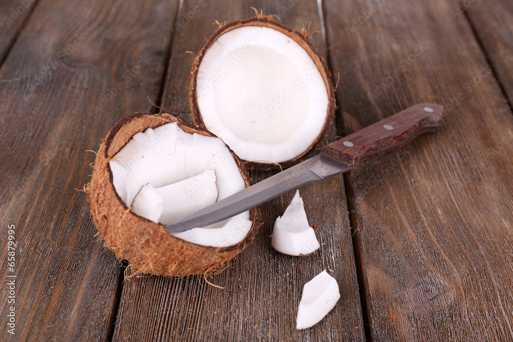 Broken coconut with knife on wooden background Broken coconut with knife on wooden background
