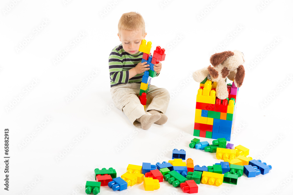 Little cute boy playing with building blocks. Isolated on white.