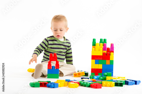 Little cute boy playing with building blocks. Isolated on white.