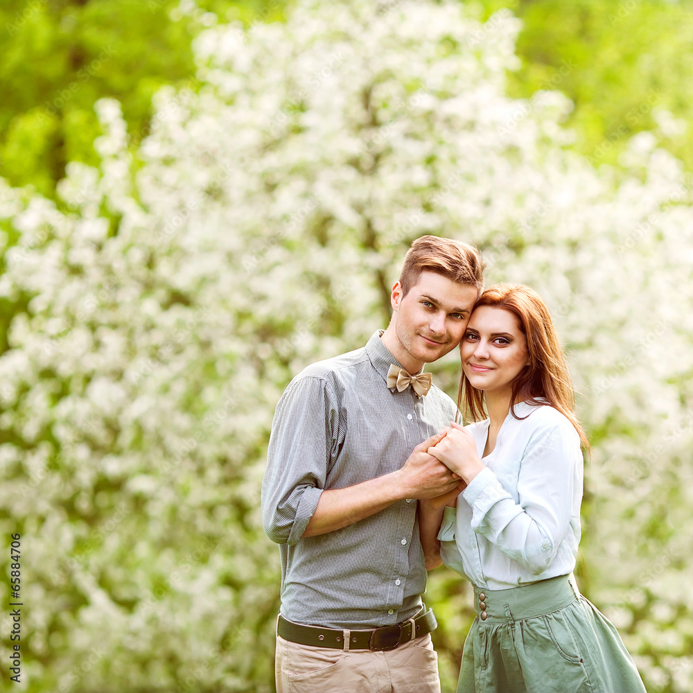 Fototapeta premium couple in love in blooming apple trees garden, smiling