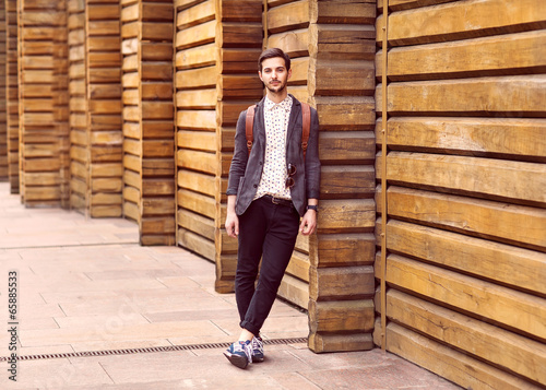 Portrait of young beautiful fashionable man against wooden wall.