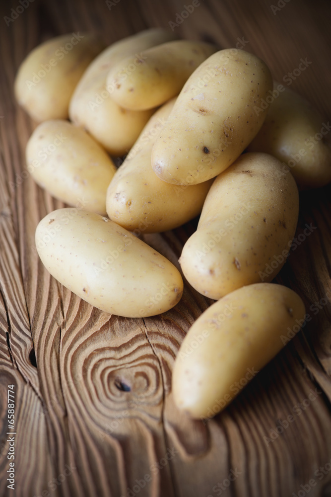 Vertical shot of freshly harvested potato over wooden surface Vertical shot of freshly harvested potato over wooden surface