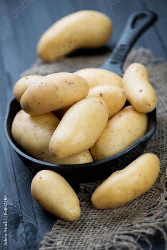 Raw potato in a frying pan over black wooden background