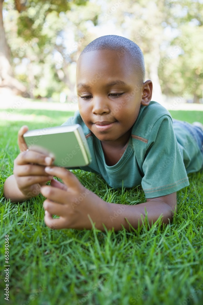 Little boy lying on grass looking at digital camera Little boy lying on grass looking at digital camera