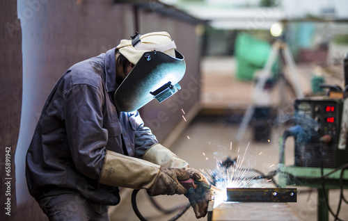 Worker with protective mask welding metal photo
