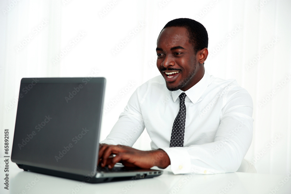 Laughing african man using laptop in office Laughing african man using laptop in office