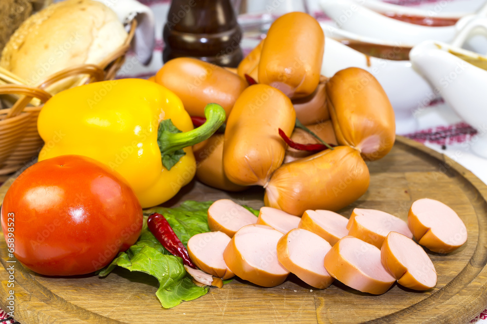 sausages on a wooden plate with vegetables in a restaurant sausages on a wooden plate with vegetables in a restaurant