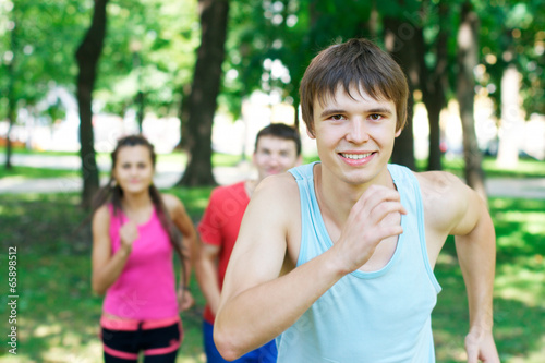 Running young happy man with a couple jogging at the background