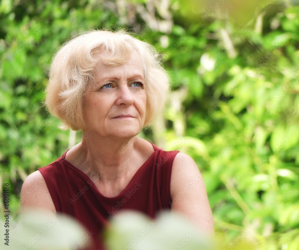 Mature, blonde woman in garden,