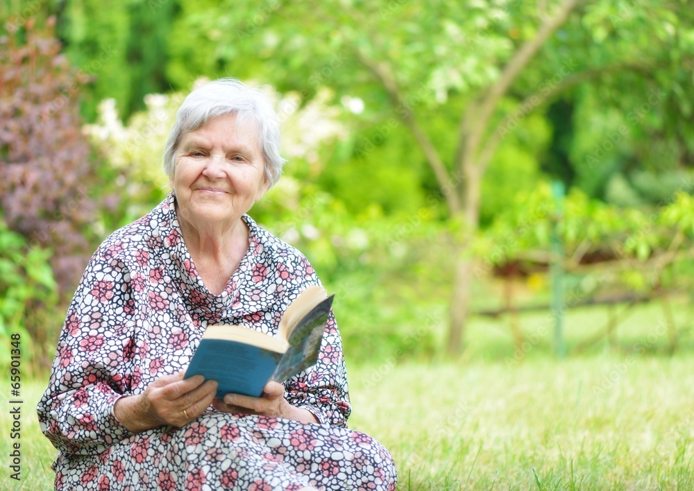 Senior woman reading book in park.