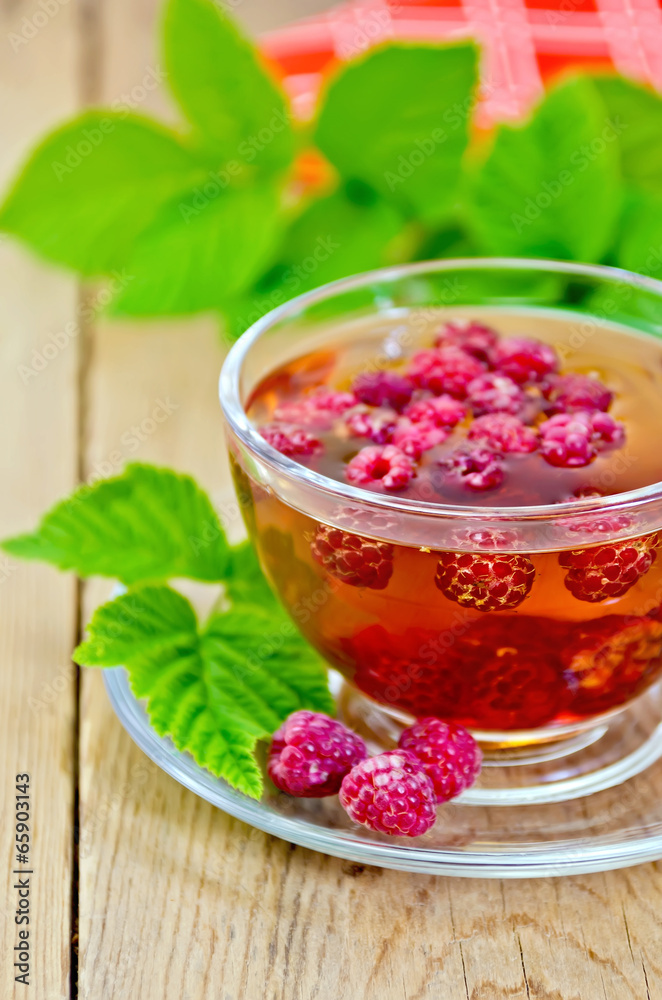 Tea with raspberries in glass cup and napkin on board Tea with raspberries in glass cup and napkin on board