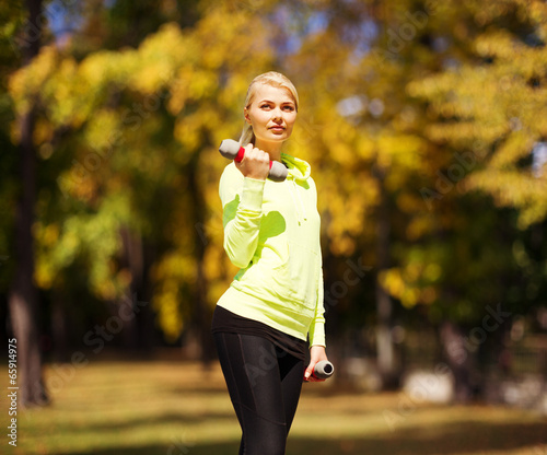 sporty woman with light dumbbells outdoors