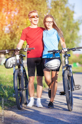 Happy and Funny Couple Walking With Bicycles in Nature Surroundi