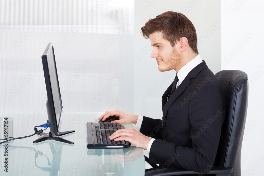 Businessman Using Computer At Office Desk Businessman Using Computer At Office Desk