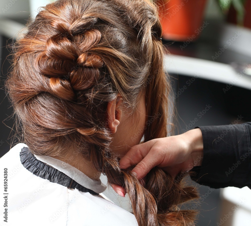 Fototapeta premium styling curls and weaving French braid on long hair in salon