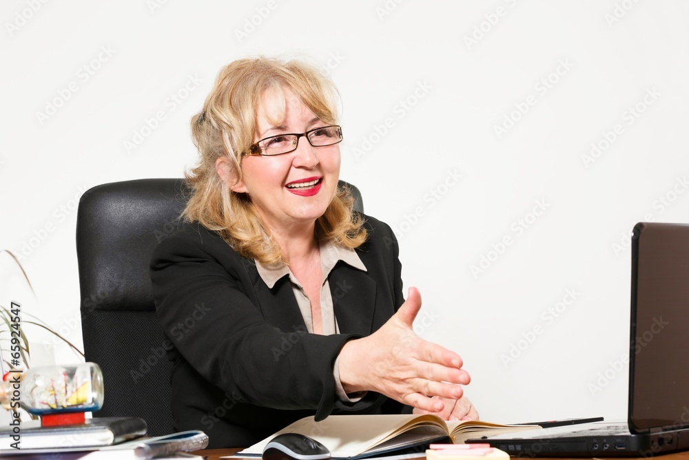 Smiling middle aged businesswoman, at the desk in office. Smiling middle aged businesswoman, at the desk in office.