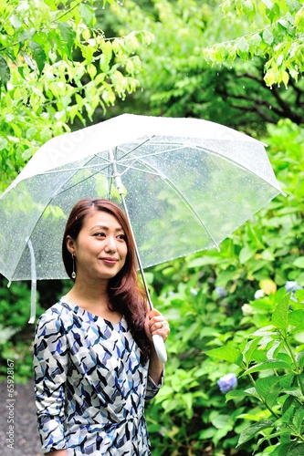 自然の緑の中で傘を差しているアジア人の女性