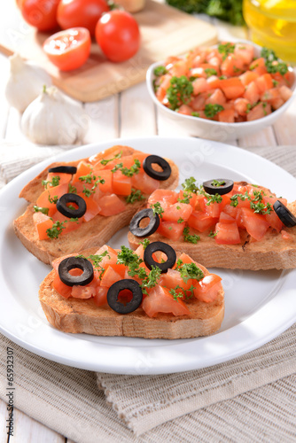 Delicious bruschetta with tomatoes on plate on table close-up © Africa Studio
