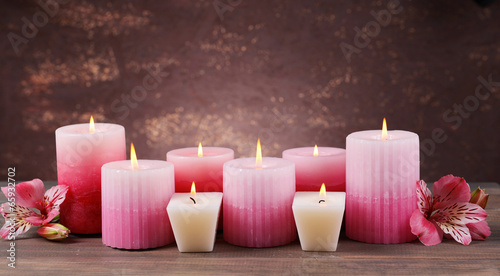Beautiful candles with flowers on table on brown background