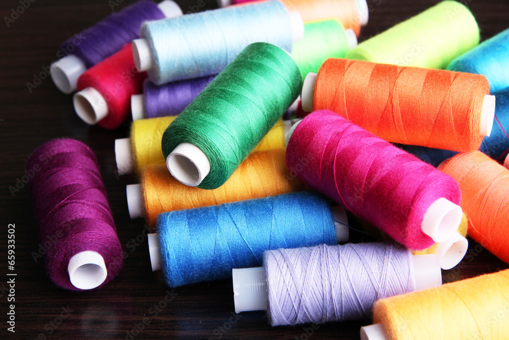 Multicolor sewing threads on wooden background Multicolor sewing threads on wooden background