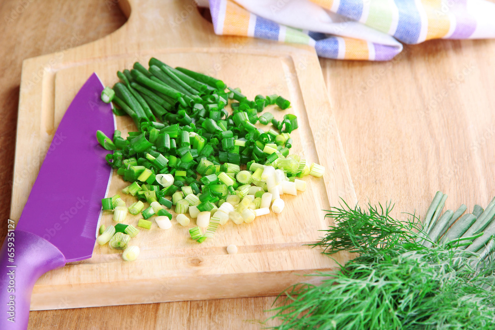 Chopped green onion with knife on cutting board on wooden table Chopped green onion with knife on cutting board on wooden table