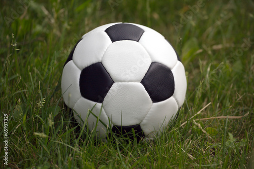 White and black ball for playing soccer in high green grass