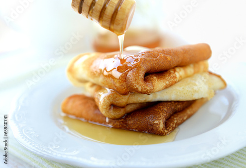 Three pancakes with butter and honey