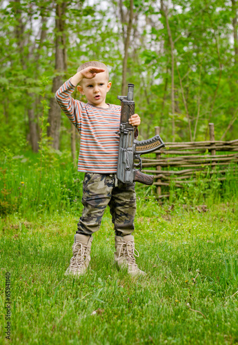 Boy carrying a machine gun saluting