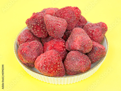 Dehydrated strawberries in a bowl on a yellow background