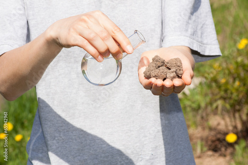 dry soil in hand and a flask with water photo