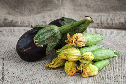 Zucchini and eggplant on wooden background and sack