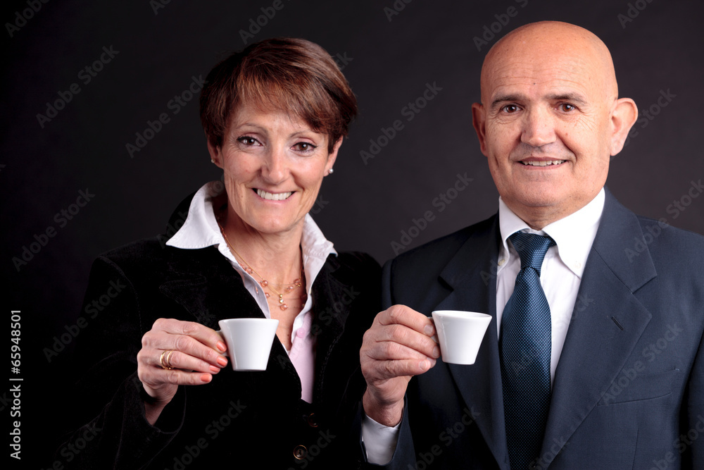 an elderly couple holding up two cups of espreso coffee an elderly couple holding up two cups of espreso coffee