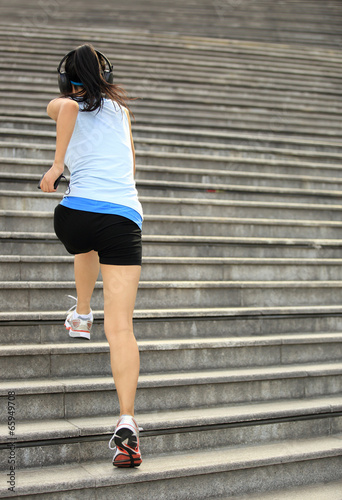 woman running listening to music in headphones from smart phone 