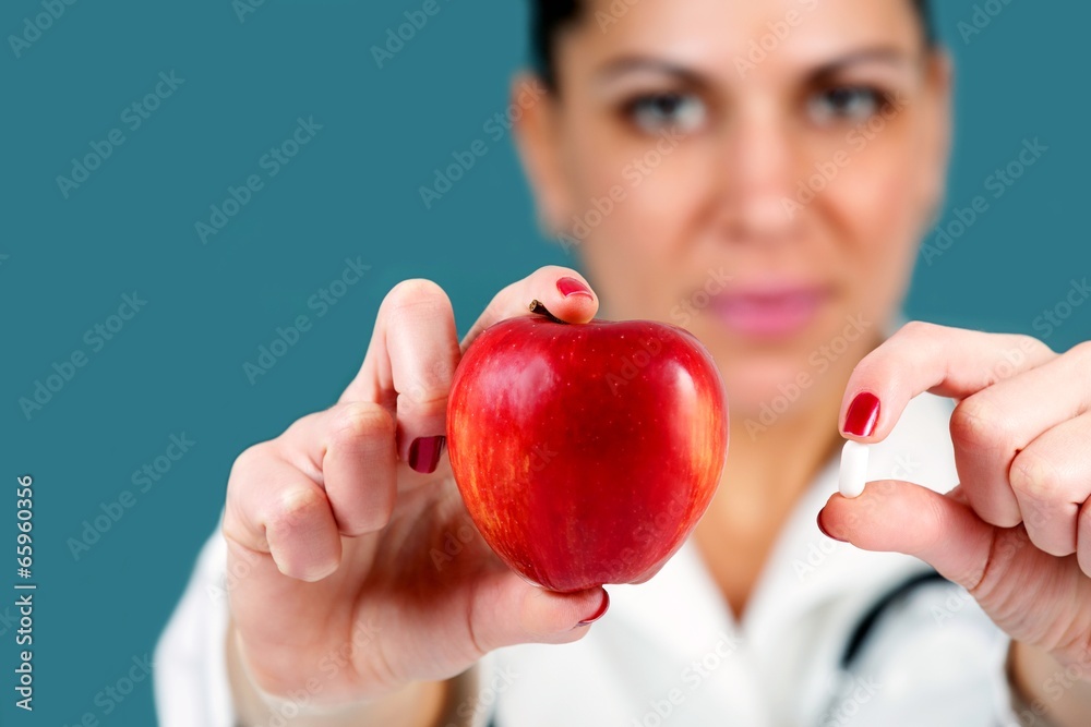 eautiful woman doctor, offering an apple and a pill eautiful woman doctor, offering an apple and a pill